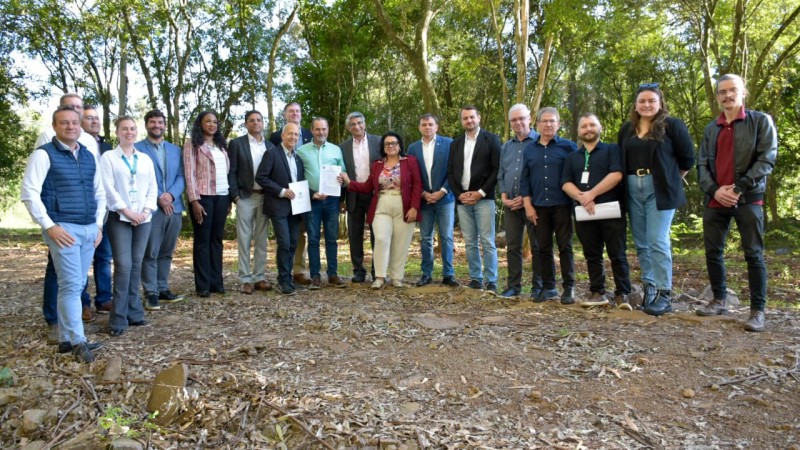 Representantes do Governo RS e representantes da Mahindra posam com a licença na área que receberá o empreendimento