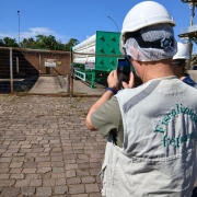Homem utilizando capacete de proteção tira foto de área de empreendimento durante vistoria da Fepam