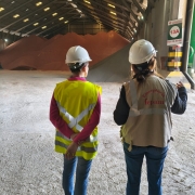 Duas pessoas utilizando capacetes de proteção observam galpão de armazenamento de minerais, em vistoria da Fepam
