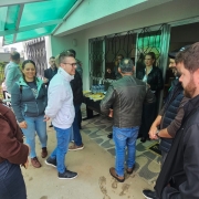 Diversas pessoas confraternizam no evento de inauguração da nova sede regional Sema-Fepam em Passo Fundo, sob pórtico de entrada da unidade. No fundo, entre as pessoas e próxima da porta, uma mesa com salgados e garrafas de água.